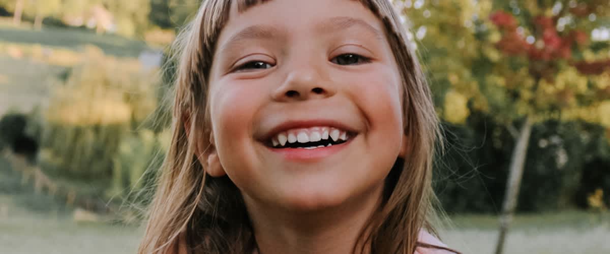 usmívající se dívka s přírodou v pozadí