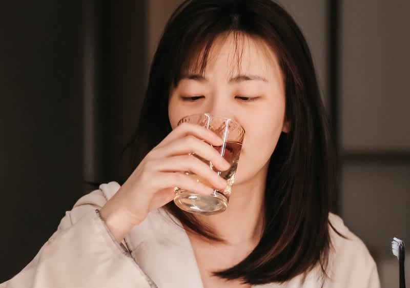 Žena v županu pije z hrnku