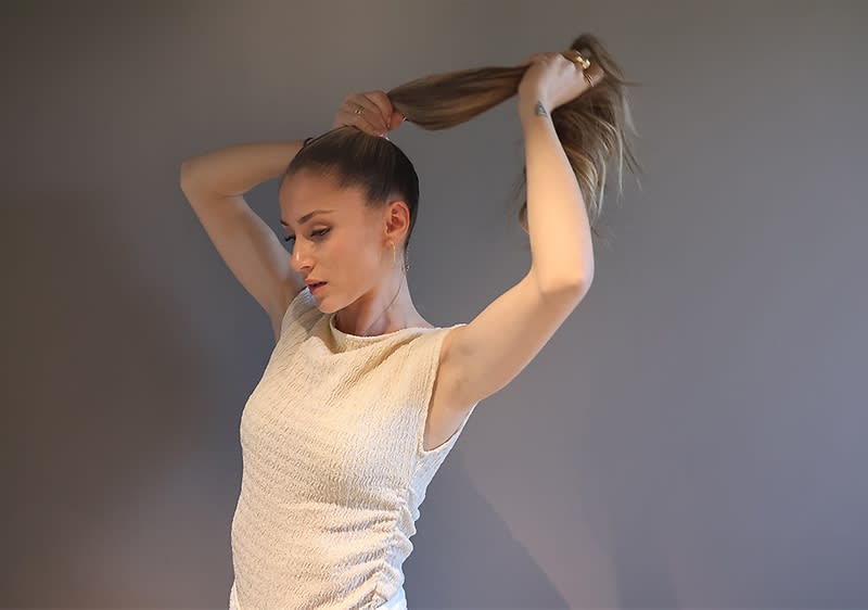 Žena si upravuje vlasy do culíku