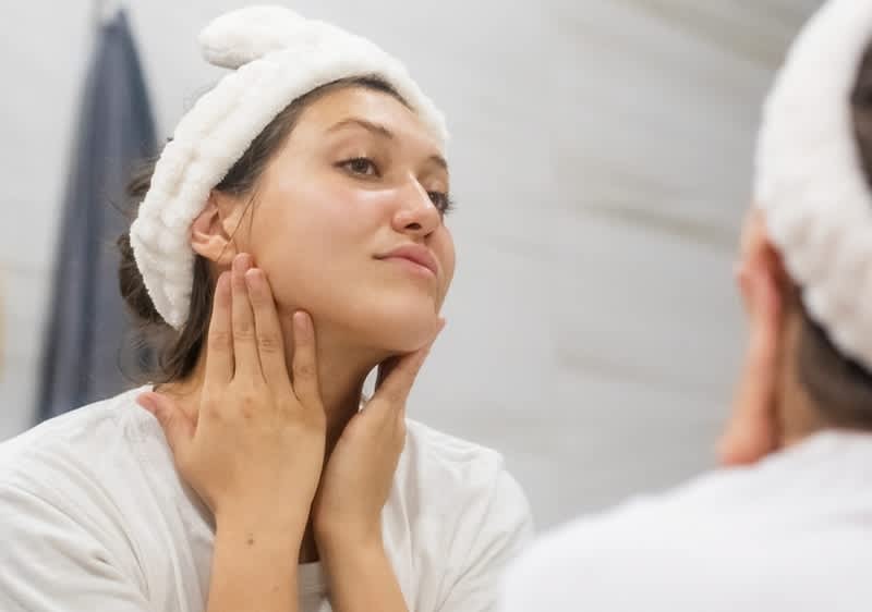 Žena v koupelně s čelenkou před zrcadlem