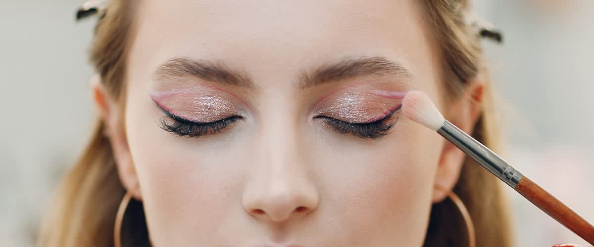 Žena nanáší make-up štětcem na tvář