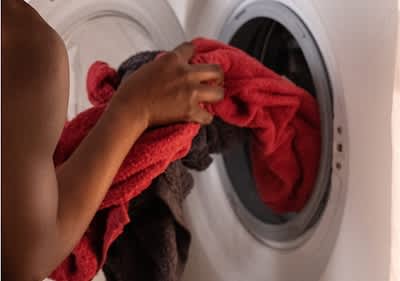 Osoba vkládá barevné prádlo do pračky