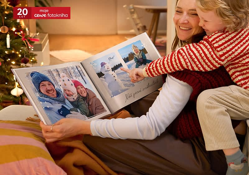 Dítě s dospělým prohlíží fotoknihu u vánočního stromku