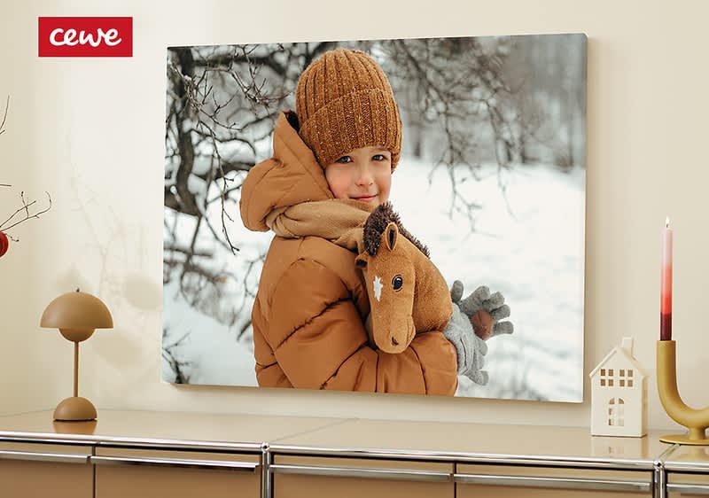 Dítě v zimním oblečení držící plyšového koně před zasněženým pozadím