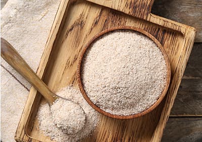 Psyllium v dřevěné misce na dřevěném prkénku s lžící