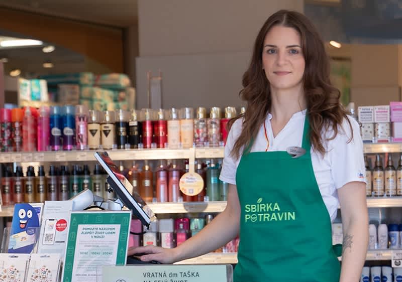 Spolupracovníčka dm v dm predajni v zelenej zástere "Sbírka potravin"