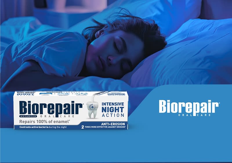 Obal zubní pasty Biorepair na modrém pozadí vedle postele s osobou