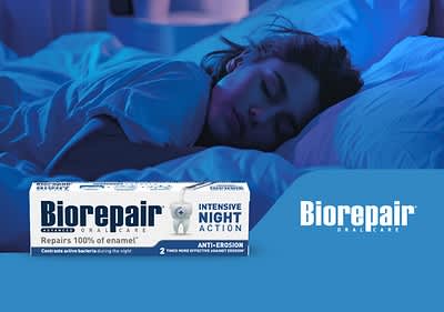 Žena spící v posteli, krabička zubní pasty Biorepair na popředí