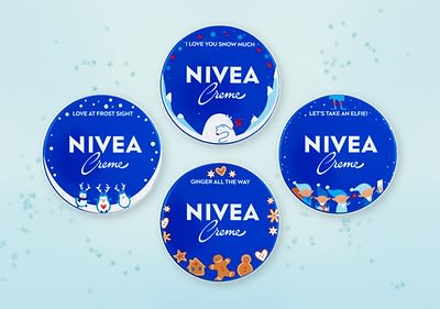 Čtyři modré plechovky Nivea s vánočními motivy a nápisy na světle modrém pozadí