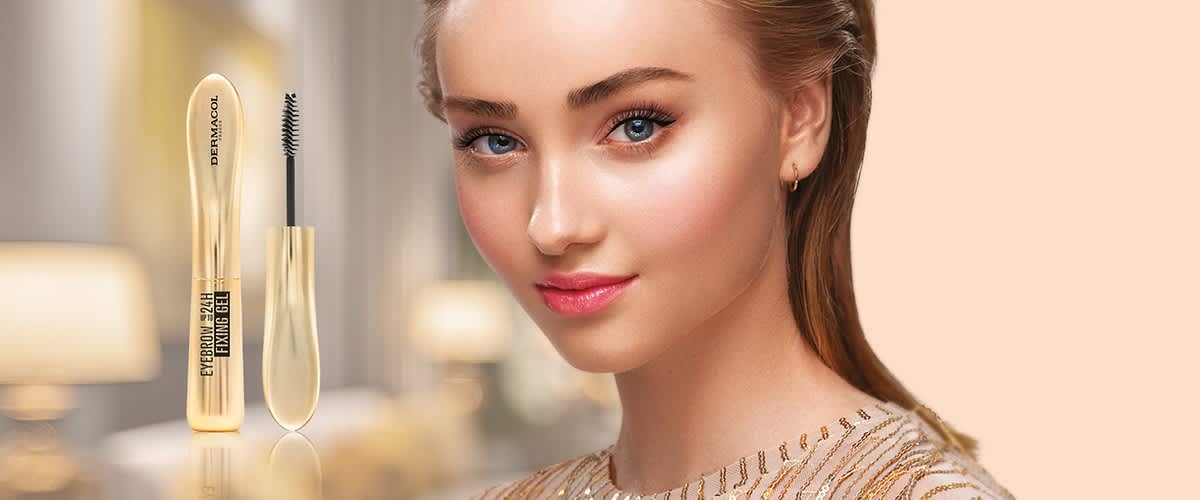 Zlatá řasenka a kartáček na pozadí rozmazané tváře ženy