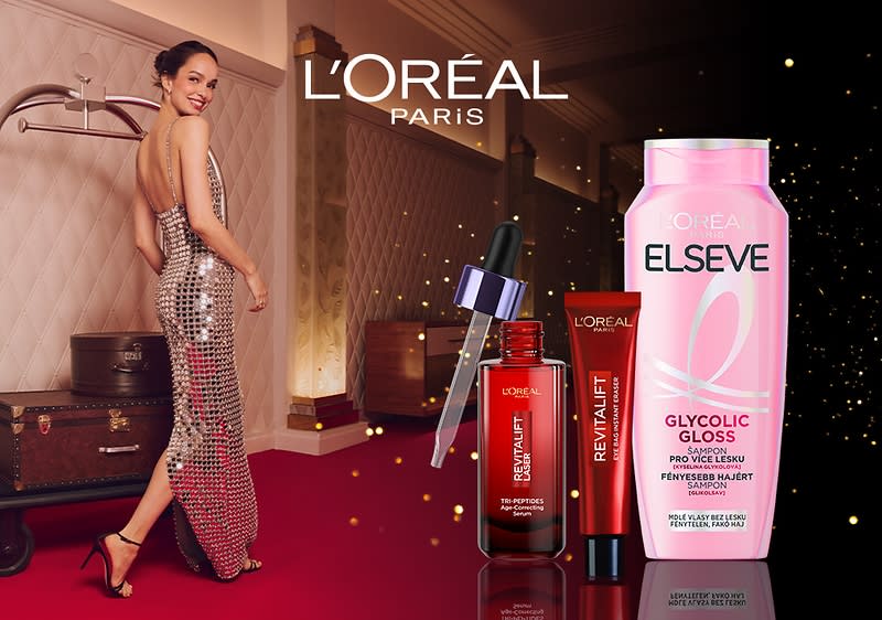 Žena v šatech, kosmetické produkty L'Oréal, kufry na pozadí