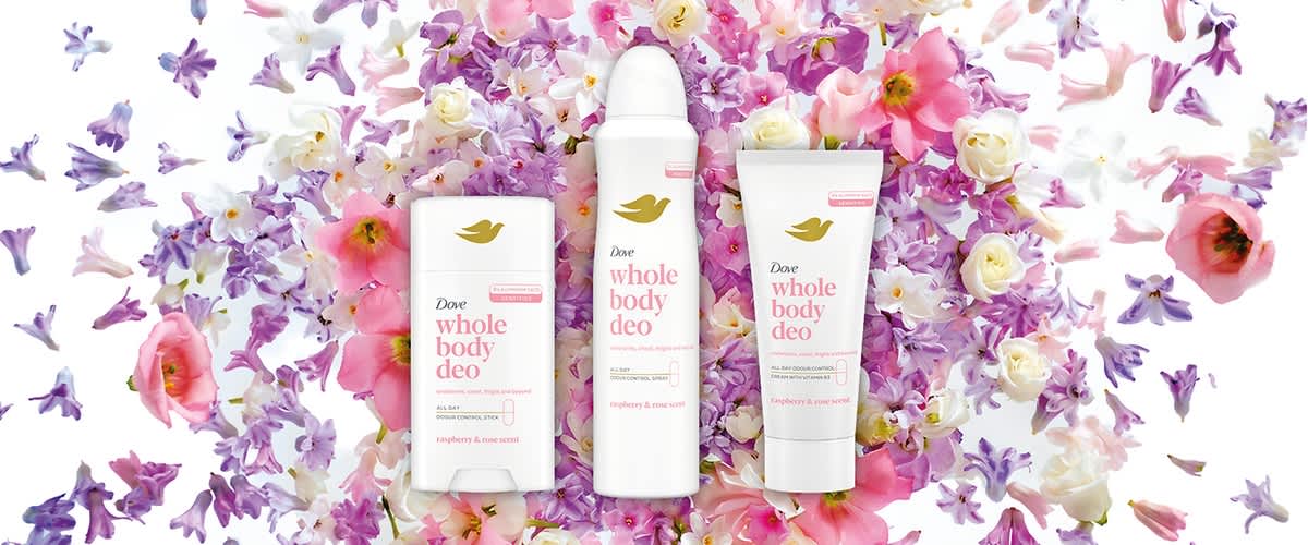 Tři produkty Dove whole body deo (tuhé, sprej, krém) na pozadí růžových a bílých květů