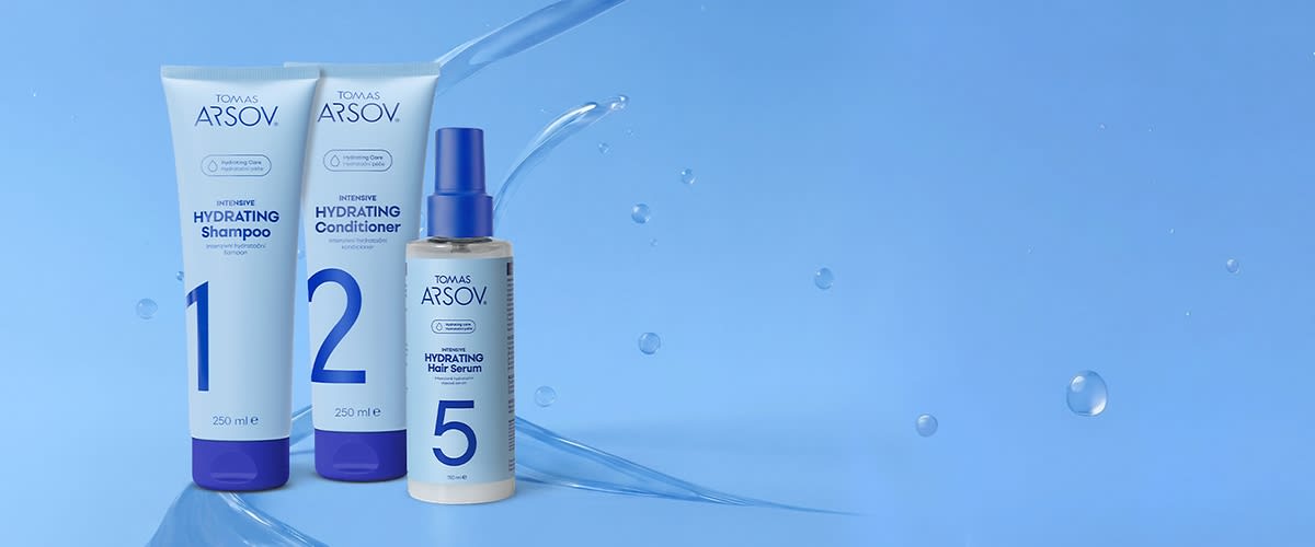 Tři modrobílé produkty vlasové péče značky TOMAS ARSOV: vlevo 250 ml tub a nápisem „1 Intensive Hydrating Shampoo“, uprostřed 250 ml tub a nápisem „2 Intensive Hydrating Conditioner“, vpravo sprejová lahvička 100 ml s nápisem „5 Hydrating Hair Serum“ na modrém pozadí s vodními kapkami