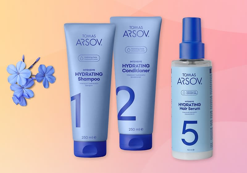 Tři modré produkty vlasové řady TOMAS ARSOV na pastelovém pozadí: vlevo 250 ml tubа s nápisem „1 Intensive Hydrating Shampoo“, uprostřed 250 ml tuba s nápisem „2 Intensive Hydrating Conditioner“, vpravo lahvička se sprejem 150 ml s nápisem „5 Intensive Hydrating Hair Serum“, vedle drobný kvítek