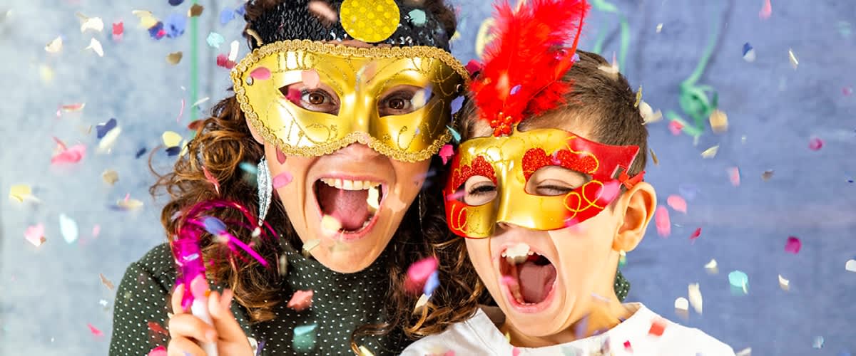 Dvě osoby v karnevalových maskách s konfety kolem nich