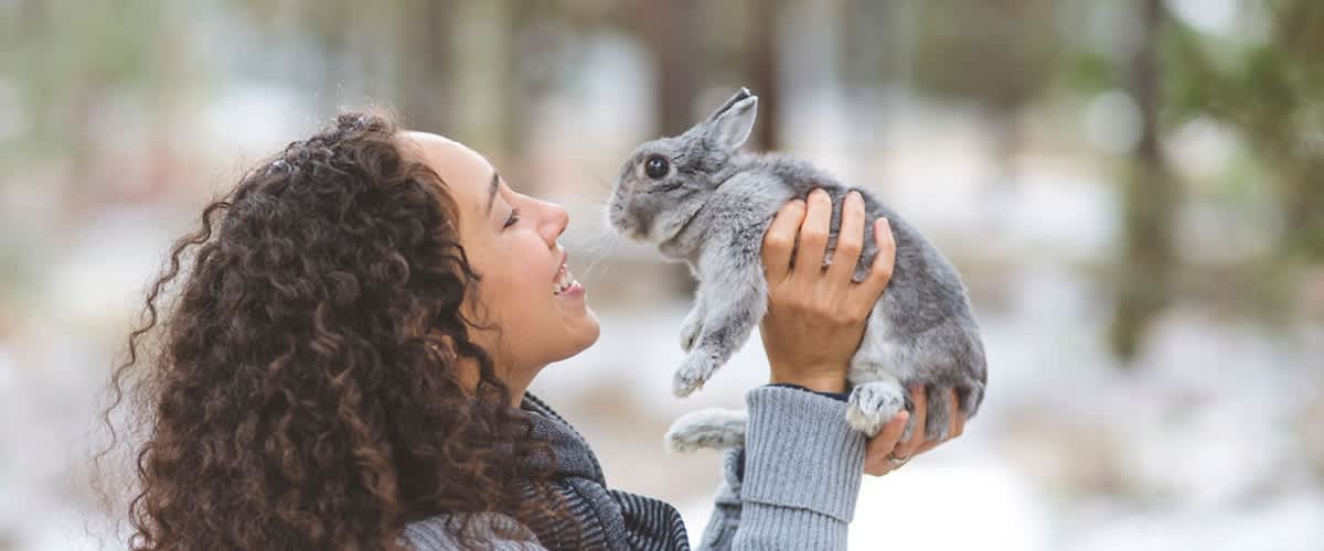 Žena držící králíka v zasněženém lese.