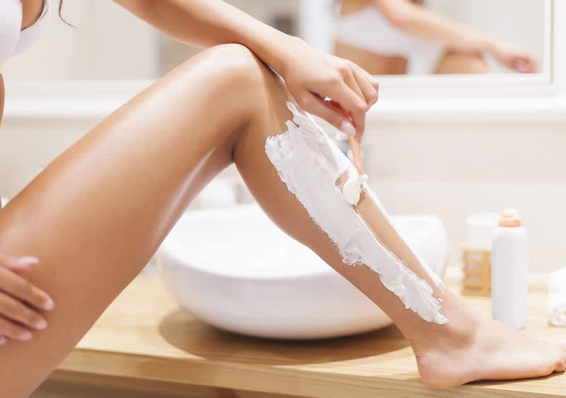 žena si holí nohy v koupelně