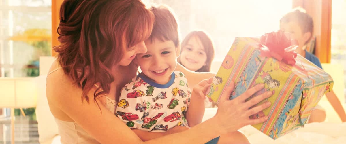Žena s dítětem drží barevně zabalený dárek.