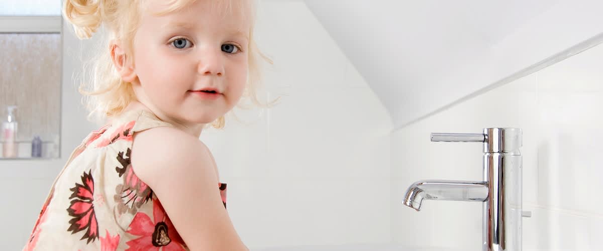 Dítě u umyvadla s květinovými šaty