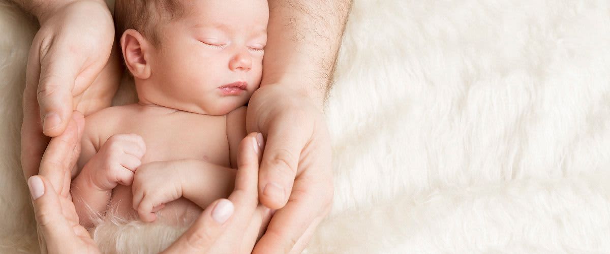 Ruka dospělého drží miminko