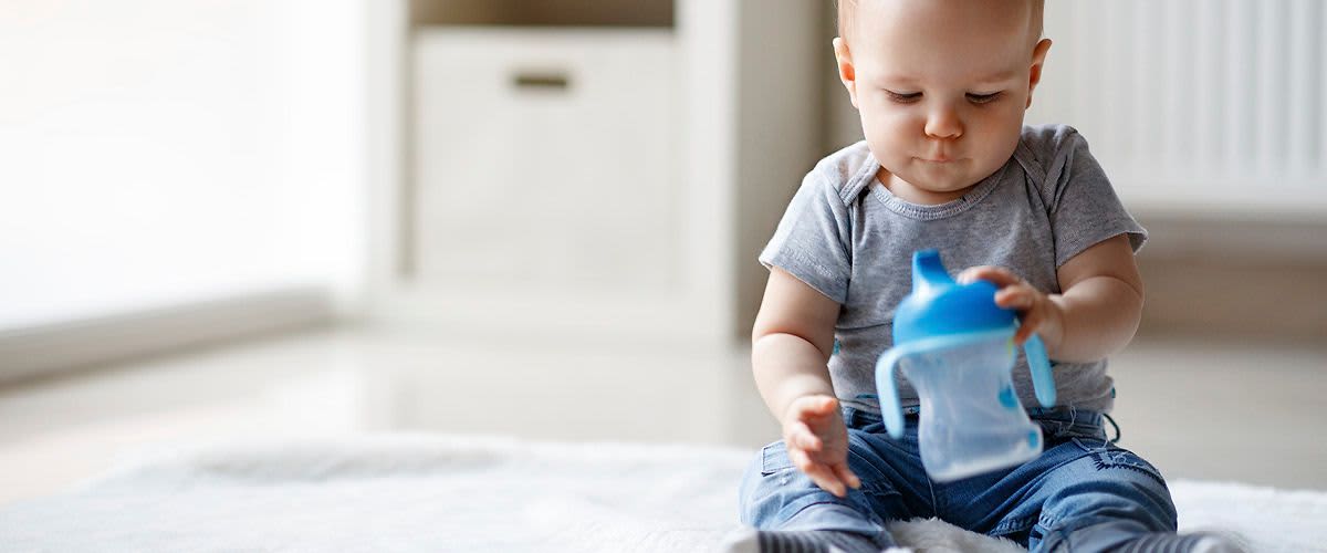 Malé dítě drží modrou dětskou láhev.