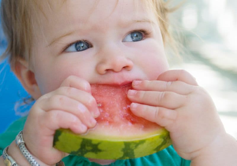 Dítě drží a jí kousek melounu