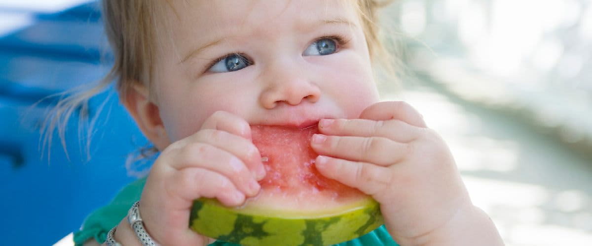 Dítě drží a jí kousek melounu