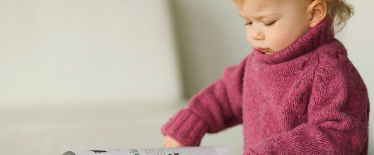 Dítě drží otevřený časopis.