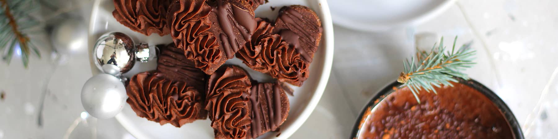 Čokoládové sušenky ve tvaru srdce na talíři, hrnek s horkou čokoládou, vánoční dekorace