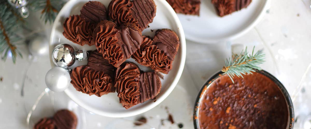 Čokoládové sušenky ve tvaru srdce na talíři, hrnek s horkou čokoládou, vánoční dekorace