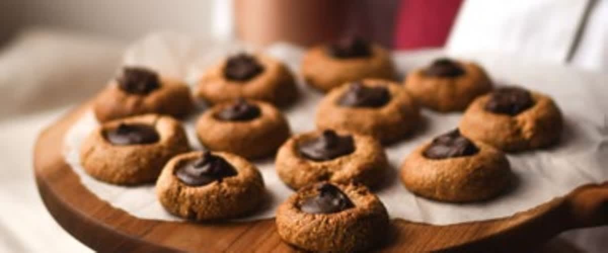 Talíř s několika sušenkami s čokoládovou náplní na papíru, držený osobou v bílé košili.