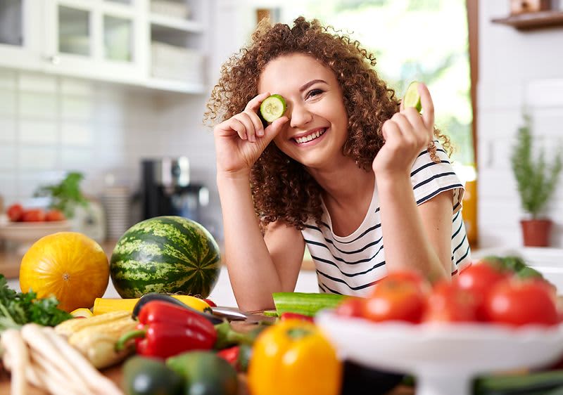 Žena v kuchyni s různými druhy ovoce a zeleniny na stole