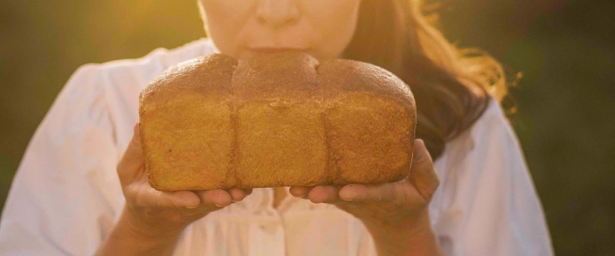 Žena držící bochník chleba na slunci