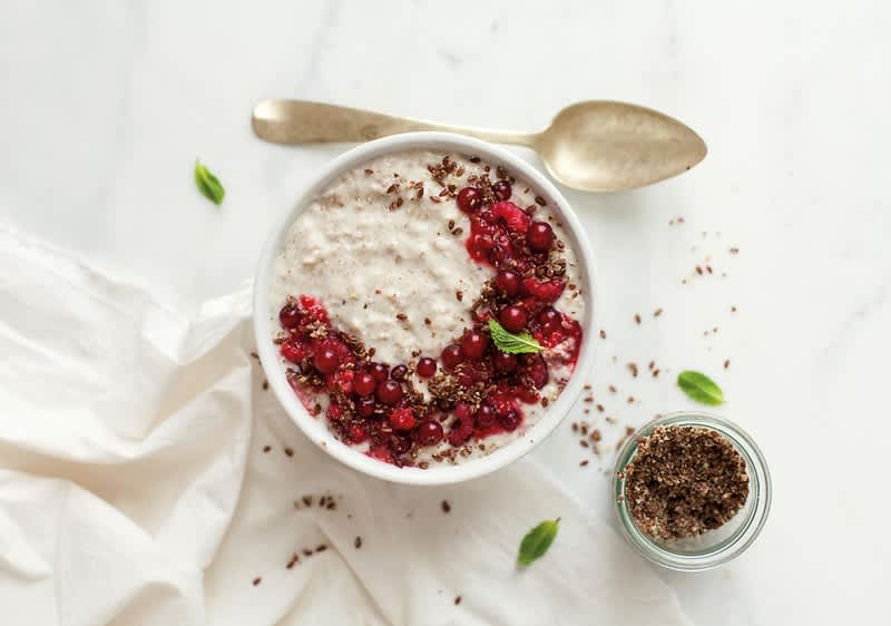 Ovesná kaše s červeným ovocem a lněnými semínky na bílém stole