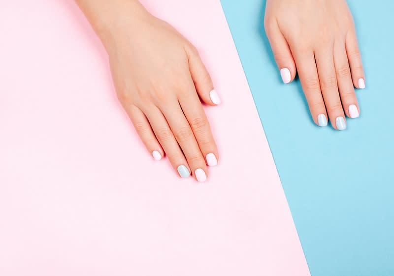 Ruce s pastelově nalakovanými nehty na růžovém a modrém pozadí
