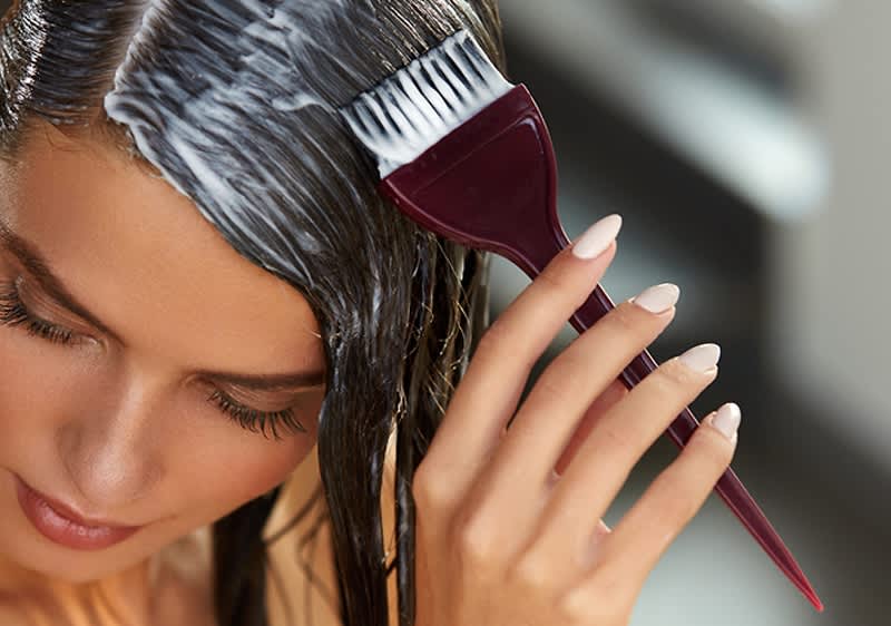 Žena nanáší barvu na vlasy štětcem