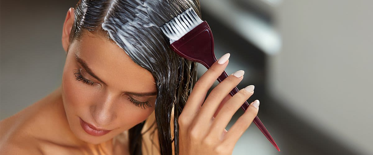 Žena nanáší barvu na vlasy štětcem