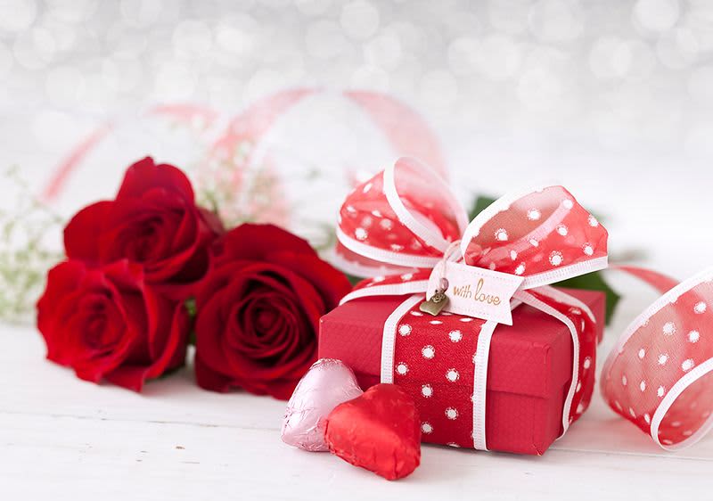 Červené růže a dárková krabička s mašlí na bílém pozadí
