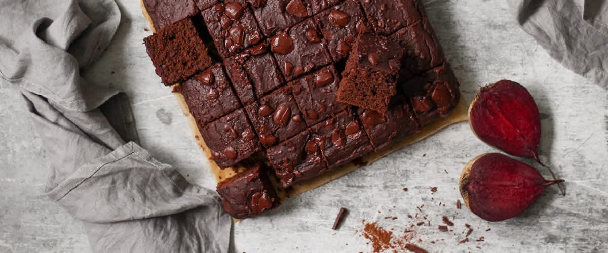 Čokoládové brownies na stole s řepou a kuchyňskými potřebami