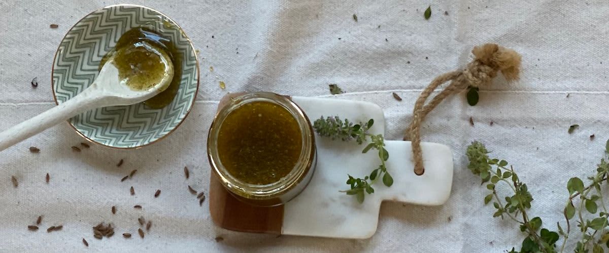 Sklenice s bylinkovým pestem na mramorovém prkénku s čerstvými bylinkami