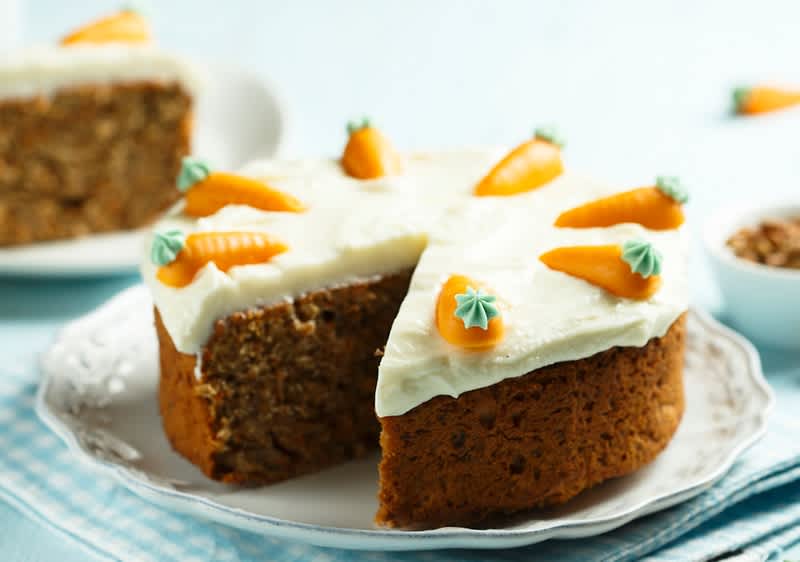 Mrkvový dort s krémem a ozdobami z marcipánových mrkviček na talíři