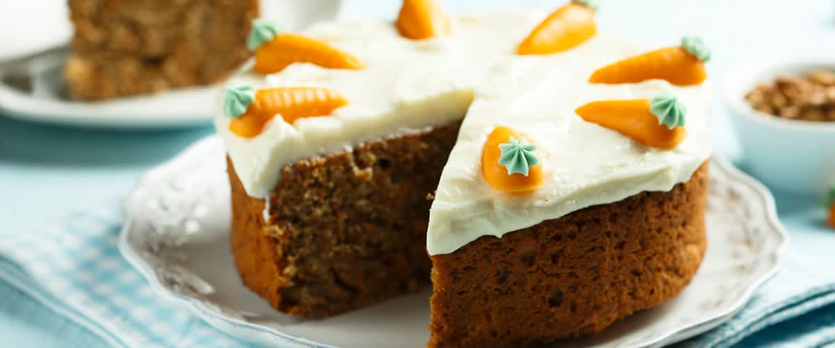 Mrkvový dort s krémem a ozdobami z marcipánových mrkviček na talíři