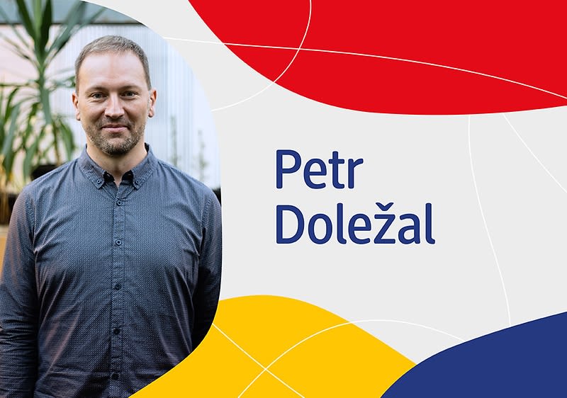Muž v šedé košili, jméno Petr Doležal, barevné pozadí s červenou, modrou a žlutou.