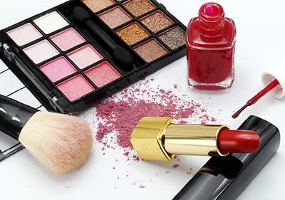 Kosmetické produkty: paletka očních stínů, červený lak na nehty, červená rtěnka, štětec na líčení, růžový pudr
