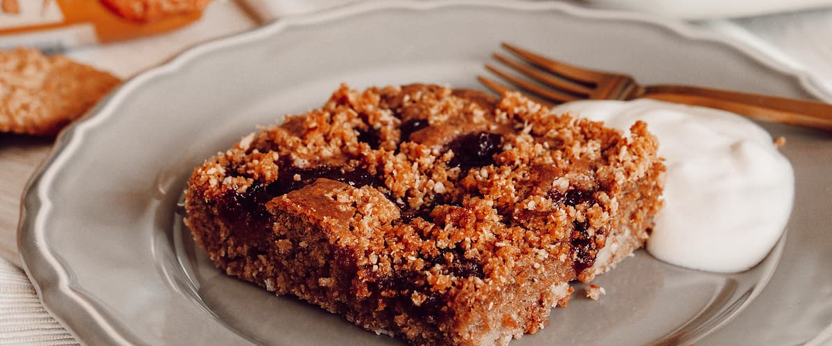 Dezert na talíři s jogurtem, v pozadí balení sušenek a sklenice másla