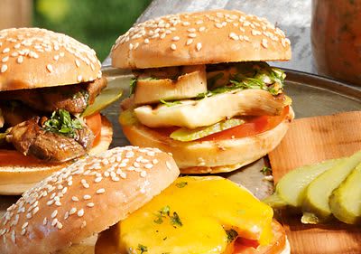 Hamburgery s houbami a sýrem, plátky okurek na dřevěném prkénku