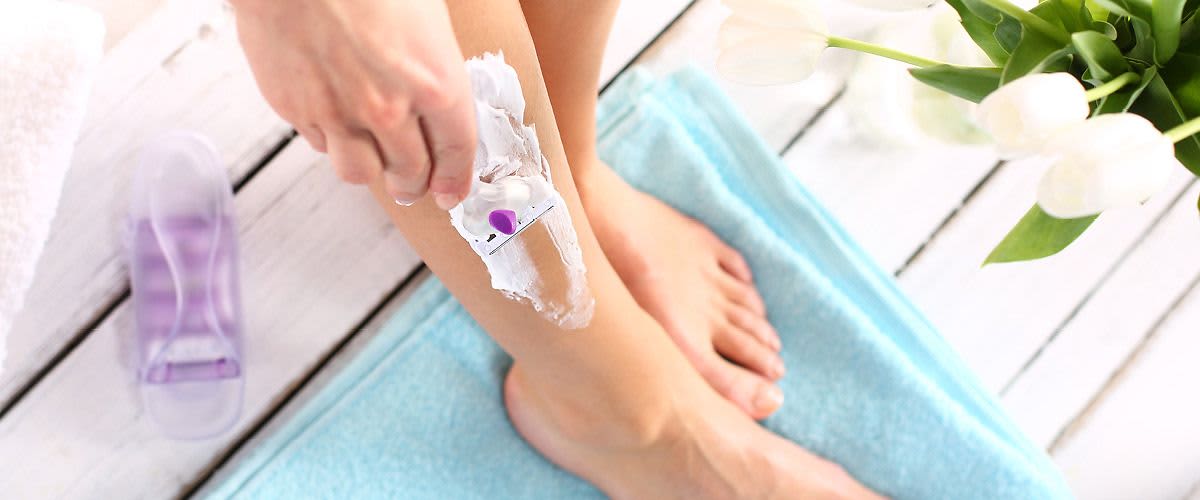 žena si holí nohy v koupelně