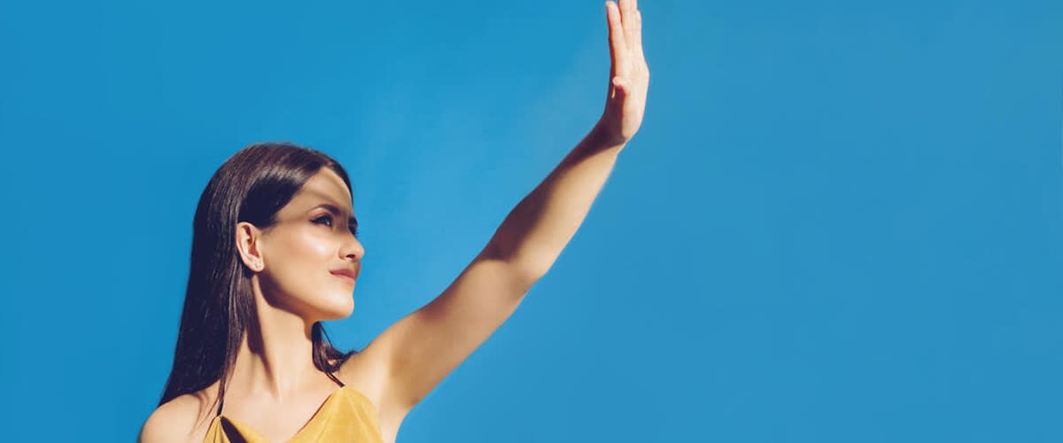 Žena zvedá ruku proti modré obloze