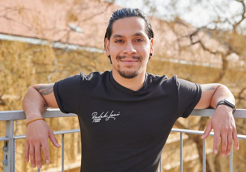 Muž v černém tričku opřený o zábradlí s rozmazaným obličejem