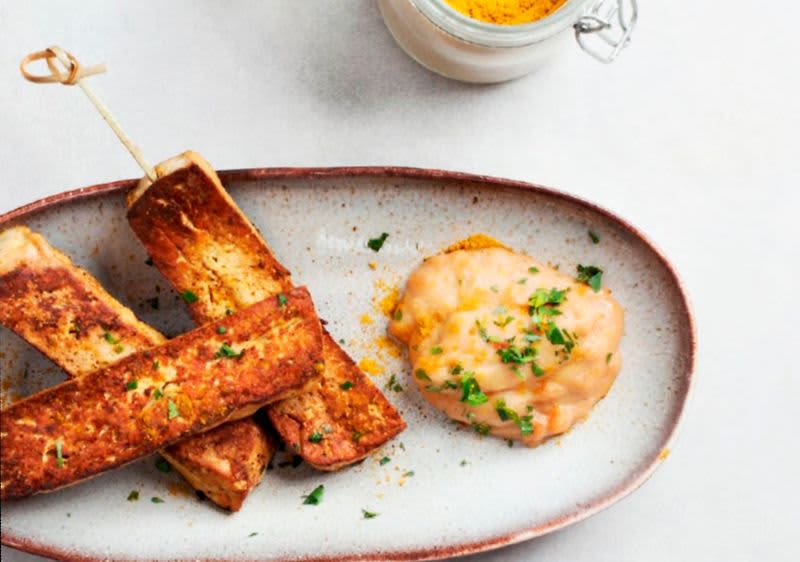 Grilované tofu tyčinky s omáčkou na talíři a sklenice s kořením
